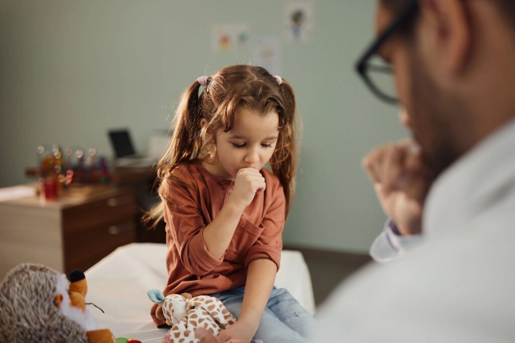Small girl coughing on appointment at doctor's office.