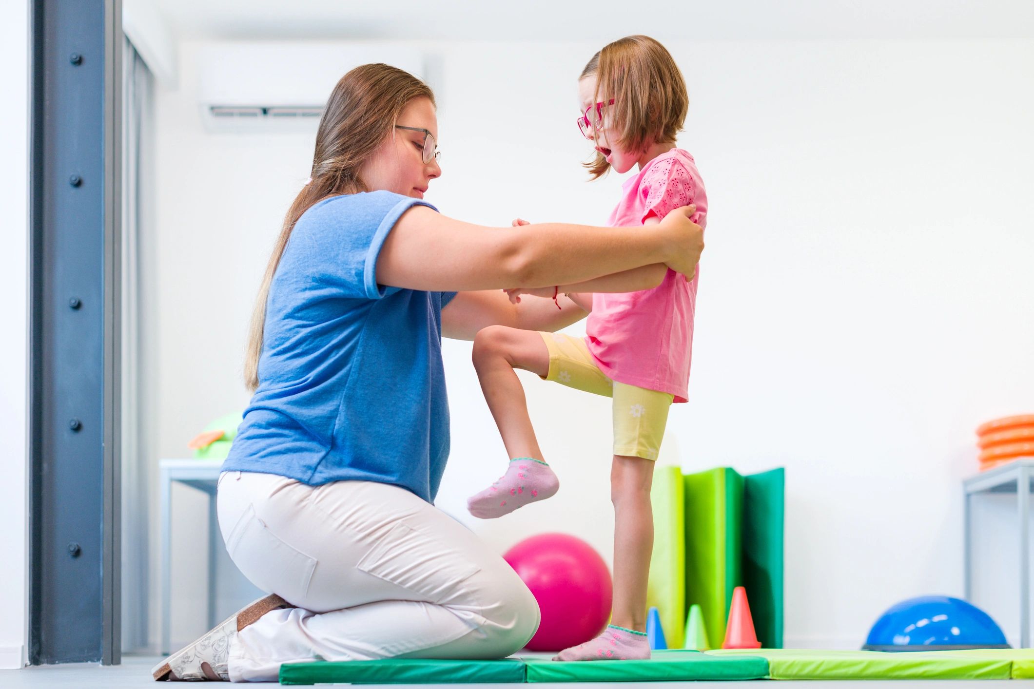 Physical therapist supporting a child during an exercise session