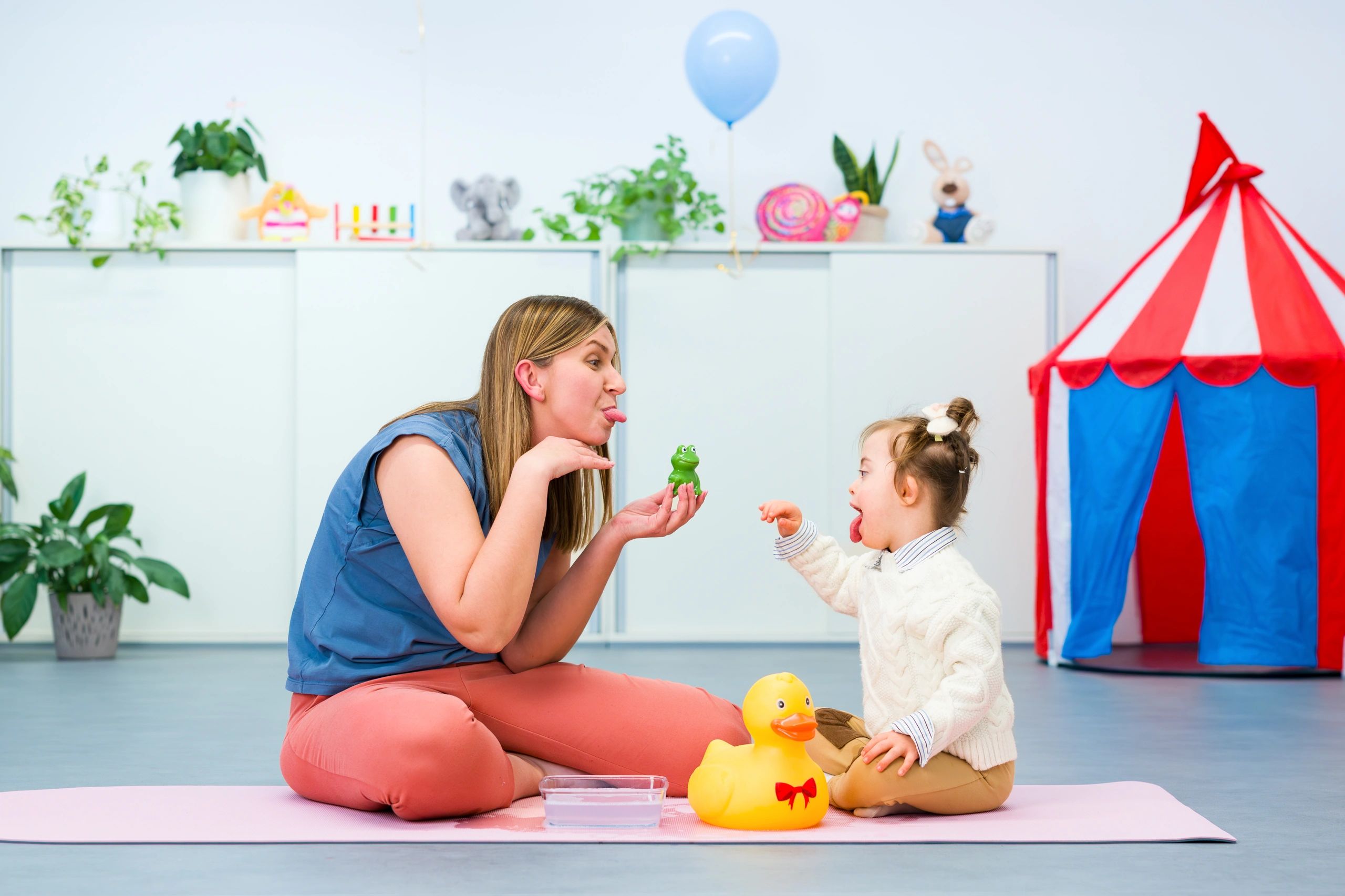Speech therapist teaching baby sign language to a child