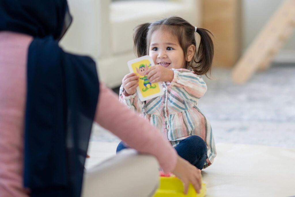 Little Girl Sharing A Colorful Card With A Caregiver In A Cozy Home Setting