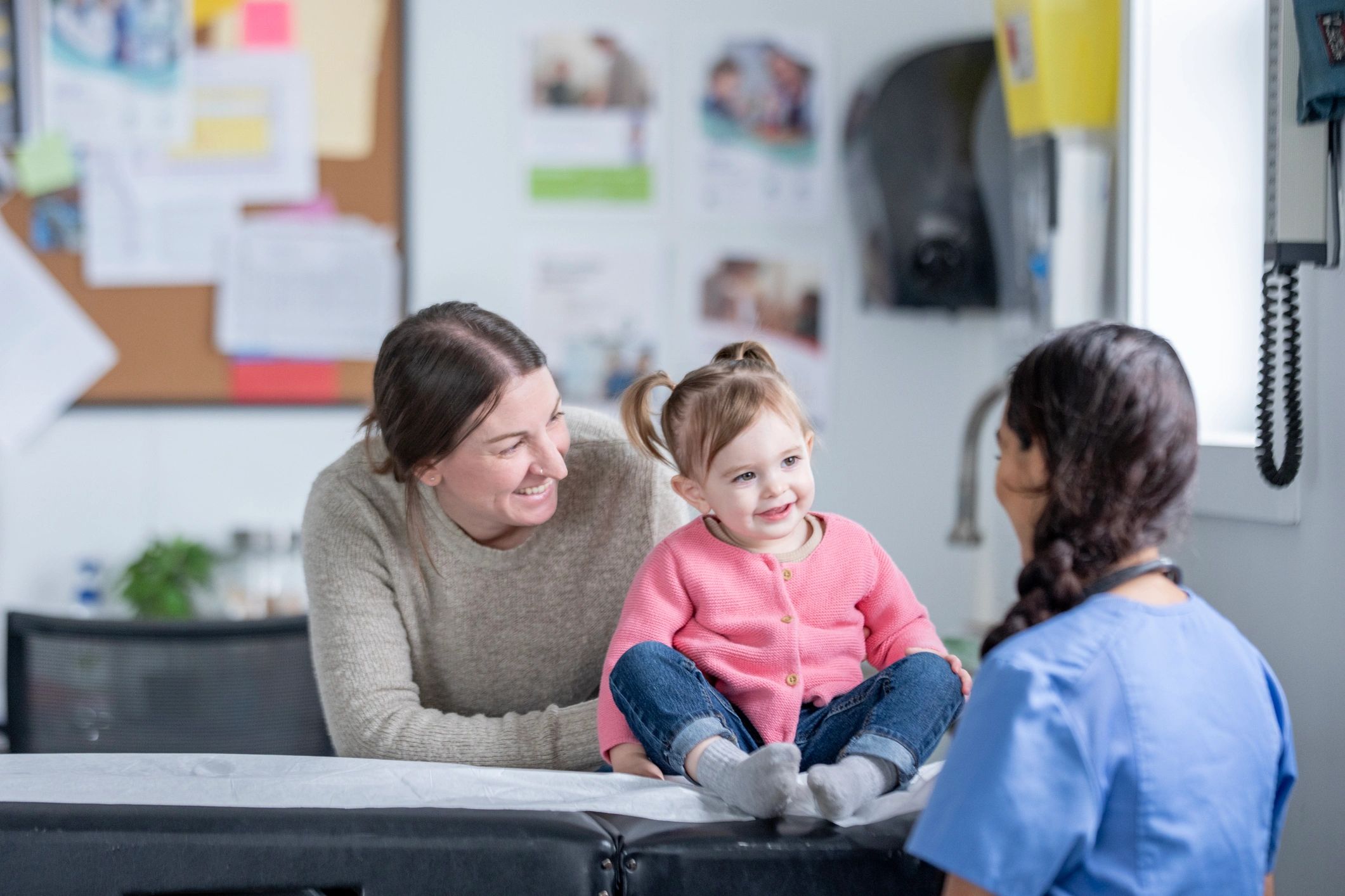 Nurse speaking with a parent and child in a friendly clinic